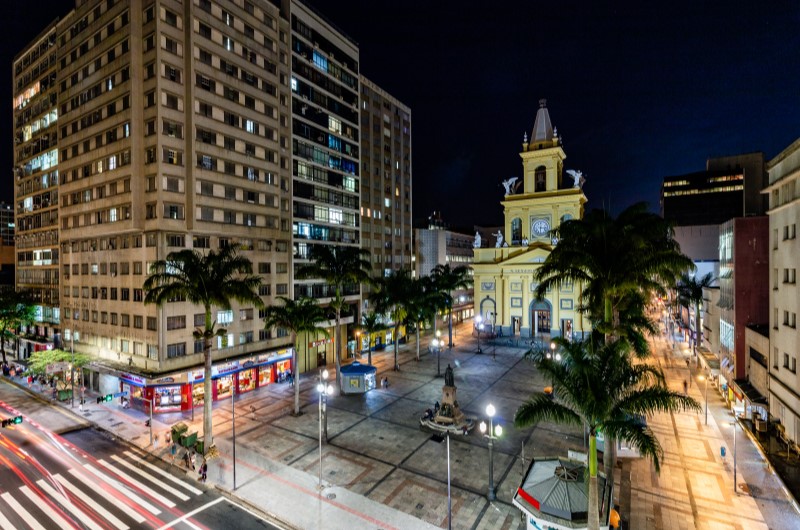 O que fazer em Campinas: veja o que fazer na cidade | Praça iluminada à noite com edifícios e a Catedral Metropolitana de Campinas ao fundo | Onde morar | Blog da Tenda 