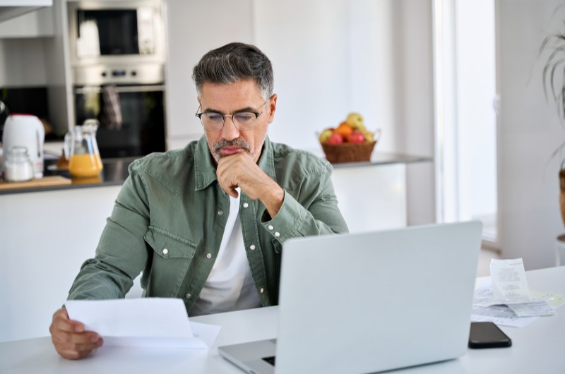 Diferença entre alienação fiduciária e financiamento | Homem concentrado lendo papéis na cozinha | Tenda Explica | Blog da Tenda 