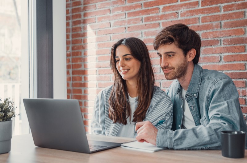 O que acontece se não pagar a alienação fiduciária | Casal sorrindo enquanto usa o notebook | Tenda Explica | Blog da Tenda 