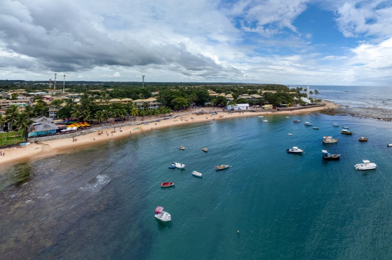 Onde fica Camaçari | Vista aérea da Praia do Forte, em Camaçari, com barcos ancorados e cidade ao fundo | Onde morar | Blog da Tenda 