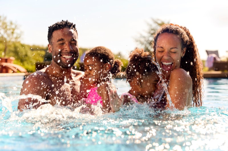 Dicas de boa convivência | Família sorrindo e brincando com respingos de água | Blog da Tenda 