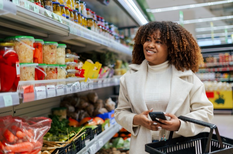 Variedade de comércios | Mulher sorridente fazendo compras em um mercado | Onde Morar | Blog da Tenda 