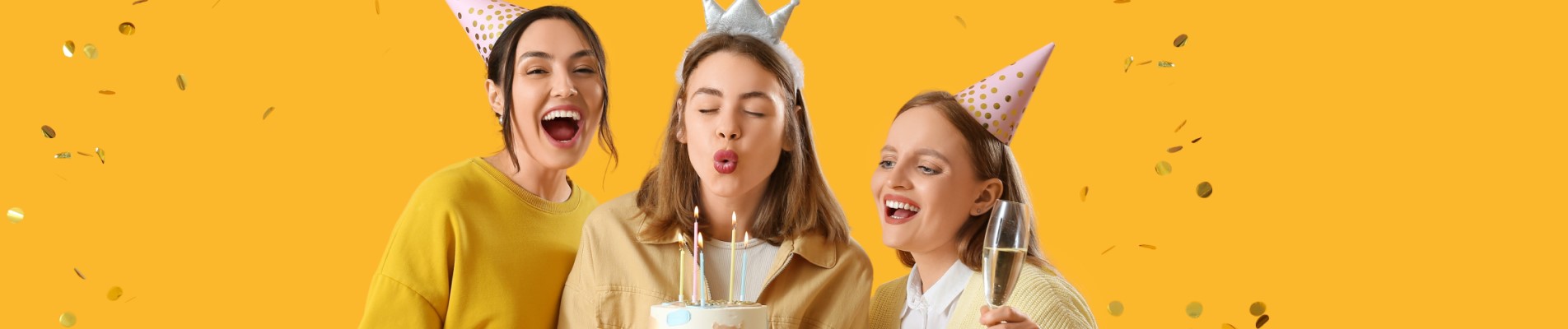 Festa de aniversário econômica: 11 dicas de como fazer | Foto de três amigas em um fundo amarelo, comemorando um aniversário com bolo e decorações coloridas | Economia e renda extra | Eu Dou Conta
