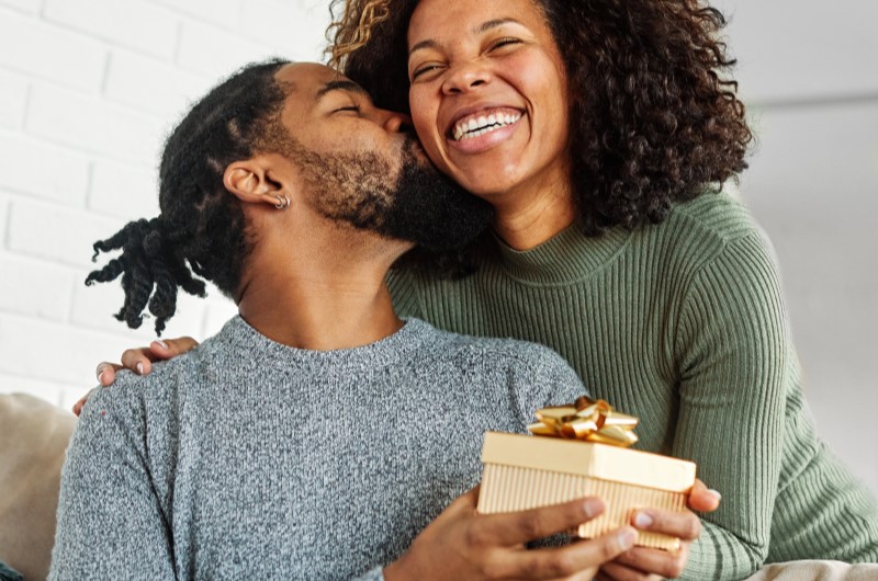 Quando é o Dia dos Namorados 2024? | Foto de um casa sorridente segurando um presente de dia dos namorados | Economia e renda extra | Eu Dou Conta