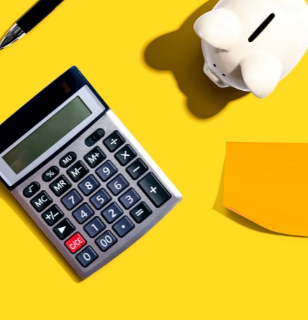 7 Dicas para limpar seu nome e sair das dívidas | Foto de um fundo amarelo com uma calculadora, um cofrinho e alguns papeis ao redor | Como limpar o seu nome | Eu Dou Conta
