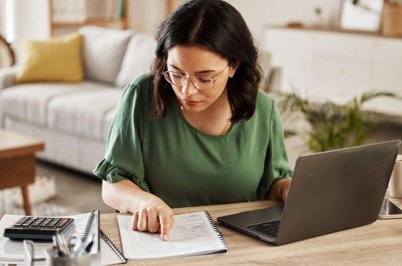 Como aplicar? | Foto de uma mulher organizando as finanças com um caderno, um notebook e uma calculadora | Economias e renda extra | Eu Dou Conta 