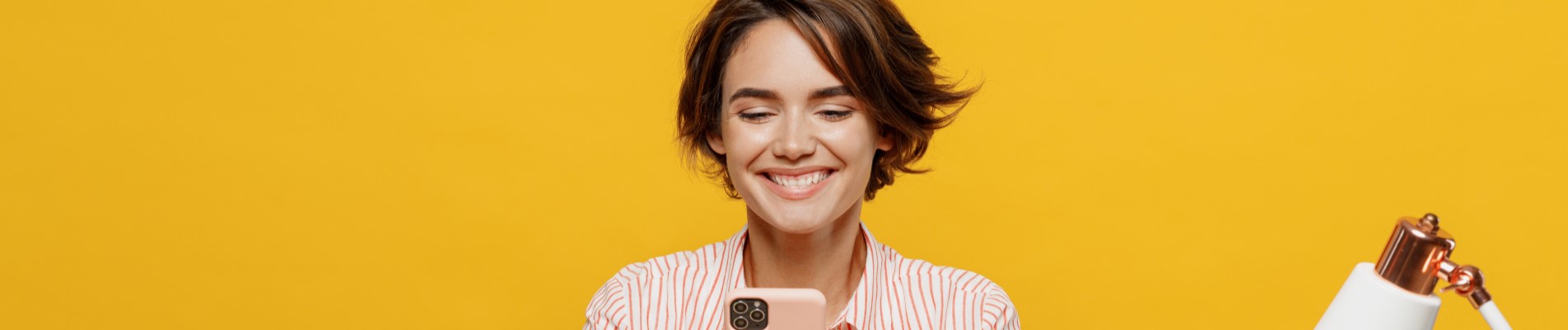 Empréstimo para CLT: como funciona e qual a melhor opção? | Foto de uma moça sorridente usando o celular | Dúvidas sobre dívidas | Eu Dou Conta